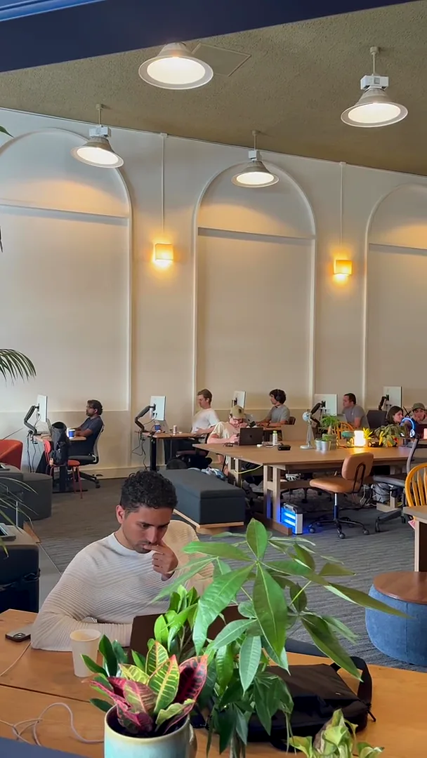 coworking sf san francisco open workspace with arched walls, plants, and members at desks with monitors