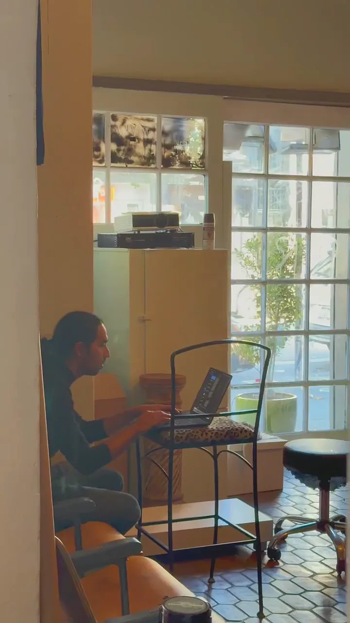 person working on laptop at small table by large windows at broadway studios, san francisco