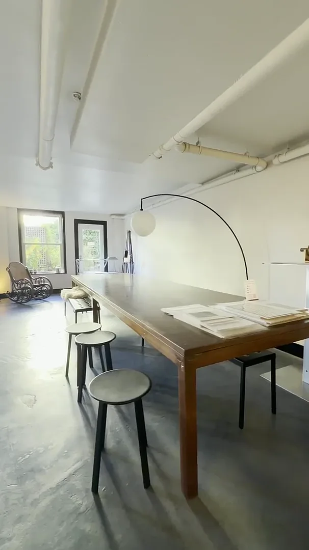 long wooden work table with stools, arc lamp, and windows in michelle thomas fine art gallery + studio, san francisco